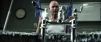 Movie still from “The Final Destination” (2009), directed by David R. Ellis – An older man in a white shirt is in front of a bathroom mirror; Medium shot, Low angle