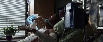 Movie still from “The Final Destination” (2009), directed by David R. Ellis – A man laying in a hospital bed with bandages on his arm; Medium shot, Overhead angle
