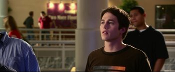 Movie still from “The Final Destination” (2009), directed by David R. Ellis – A man standing in front of a building with lights in the background; Close Up shot, Over the shoulder angle