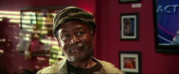 Movie still from “The Final Destination” (2009), directed by David R. Ellis – An older man wearing a hat in a red room; Close Up shot, High angle