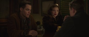 Movie still from “The Finest Hours” (2016), directed by Craig Gillespie – A man and a woman sitting at a table with drinks; Medium shot, Over the shoulder angle