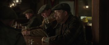 Movie still from “The Finest Hours” (2016), directed by Craig Gillespie – Two men sitting at a table drinking a glass of beer; Medium shot, Over the shoulder angle