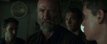 Movie still from “The Finest Hours” (2016), directed by Craig Gillespie – A man with a gray beard is looking at the camera; Close Up shot, Over the shoulder angle