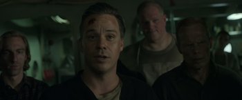 Movie still from “The Finest Hours” (2016), directed by Craig Gillespie – A man with a bandage on his head is standing next to another man with a bandage on his head; Close Up shot, Low angle