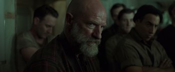 Movie still from “The Finest Hours” (2016), directed by Craig Gillespie – An old man with a beard and a goatee looking into the camera; Close Up shot, Over the shoulder angle