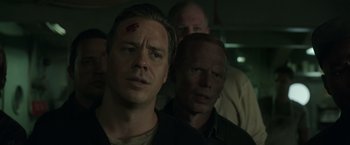 Movie still from “The Finest Hours” (2016), directed by Craig Gillespie – A man with a bandage on his head is standing next to another man with a bandage on his head; Close Up shot, Over the shoulder angle