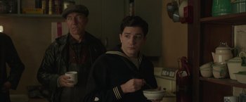 Movie still from “The Finest Hours” (2016), directed by Craig Gillespie – A man in a sailor's uniform holding a bowl of food; Medium shot, Over the shoulder angle