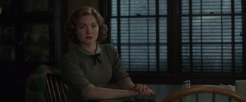 Movie still from “The Finest Hours” (2016), directed by Craig Gillespie – A woman sitting at a table in front of a window; Medium shot, Over the shoulder angle