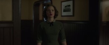 Movie still from “The Finest Hours” (2016), directed by Craig Gillespie – A woman in a green dress standing in front of a wall; Medium shot, Low angle