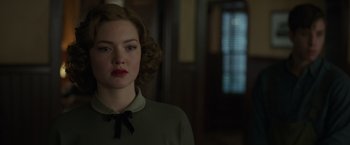 A woman with red lipstick is standing in front of a door