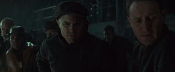 Movie still from “The Finest Hours” (2016), directed by Craig Gillespie – A man in a hat and a black jacket is in a dark room; Close Up shot, Low angle