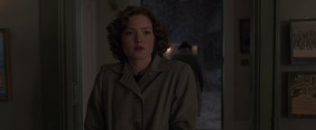 Movie still from “The Finest Hours” (2016), directed by Craig Gillespie – A woman in a trench coat standing in front of a window; Medium shot, Over the shoulder angle