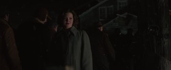 Movie still from “The Finest Hours” (2016), directed by Craig Gillespie – A woman standing in the dark wearing a coat; Medium shot, Over the shoulder angle