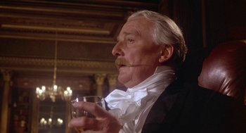 Movie still from “The Great Train Robbery” (1978), directed by Michael Crichton – An older man in a suit holding a glass of wine; Close Up shot, Low angle