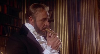 Movie still from “The Great Train Robbery” (1978), directed by Michael Crichton – A man in a suit and a white shirt is smoking a cigar; Close Up shot, Low angle