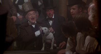 Movie still from “The Great Train Robbery” (1978), directed by Michael Crichton – A group of men in top hats holding a white dog; Medium shot, Low angle