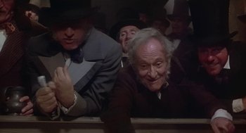 Movie still from “The Great Train Robbery” (1978), directed by Michael Crichton – A group of people in a room with a man in a suit and a hat; Medium shot, Low angle