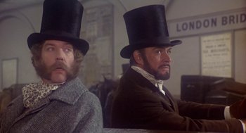 Movie still from “The Great Train Robbery” (1978), directed by Michael Crichton – Two men in top hats and jackets sitting next to each other; Medium shot, Low angle