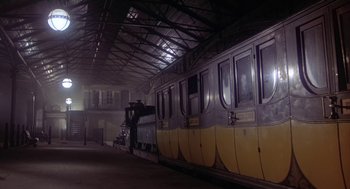Movie still from “The Great Train Robbery” (1978), directed by Michael Crichton – A yellow and gray train is parked in a train station; Extreme Wide shot, Low angle