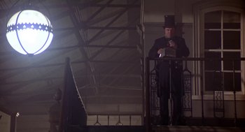 Movie still from “The Great Train Robbery” (1978), directed by Michael Crichton – A man in a top hat standing next to a railing; Wide shot, Low angle