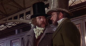 Movie still from “The Great Train Robbery” (1978), directed by Michael Crichton – A man in a top hat and a man in a coat and tie; Medium shot, Low angle