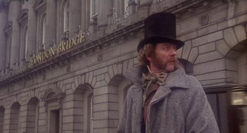 Movie still from “The Great Train Robbery” (1978), directed by Michael Crichton – A man wearing a top hat and a long coat standing in front of a building; Medium shot, Low angle