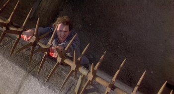 Movie still from “The Great Train Robbery” (1978), directed by Michael Crichton – A man is climbing over a fence with spikes; Medium shot, Overhead angle