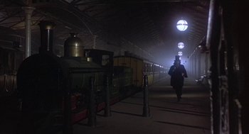 Movie still from “The Great Train Robbery” (1978), directed by Michael Crichton – A man is walking in a train station at night; Wide shot, Low angle