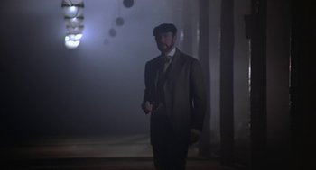 Movie still from “The Great Train Robbery” (1978), directed by Michael Crichton – A man in a suit and hat standing in a dark room; Medium shot, Low angle