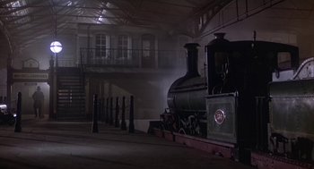 Movie still from “The Great Train Robbery” (1978), directed by Michael Crichton – An old steam engine train sitting in a train station; Extreme Wide shot, Low angle