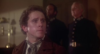 Movie still from “The Great Train Robbery” (1978), directed by Michael Crichton – A man in a suit and tie standing in front of two other men; Close Up shot, Over the shoulder angle