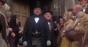 Movie still from “The Great Train Robbery” (1978), directed by Michael Crichton – A man in a top hat is standing in front of a group of people; Medium shot, Low angle