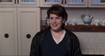 Movie still from “The First Wives Club” (1996), directed by Hugh Wilson – A woman wearing a leather jacket standing in a kitchen; Medium shot, Over the shoulder angle