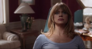 Movie still from “The First Wives Club” (1996), directed by Hugh Wilson – A woman in a blue shirt is standing in front of a lamp; Close Up shot, Low angle