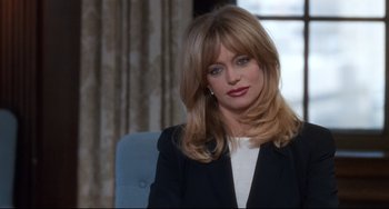 Movie still from “The First Wives Club” (1996), directed by Hugh Wilson – A person sitting in a chair wearing a suit; Close Up shot, High angle