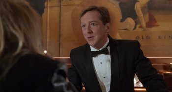 Movie still from “The First Wives Club” (1996), directed by Hugh Wilson – A man wearing a tuxedo and a bow tie in front of a painting; Close Up shot, Over the shoulder angle