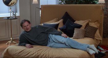 Movie still from “The First Wives Club” (1996), directed by Hugh Wilson – A man laying on a bed in a room; Medium shot, High angle