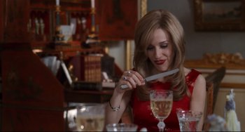 Movie still from “The First Wives Club” (1996), directed by Hugh Wilson – A woman in a red dress holding a knife in her hand; Medium shot, High angle
