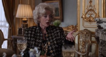 Movie still from “The First Wives Club” (1996), directed by Hugh Wilson – An older woman wearing a black and gold jacket; Medium shot, Over the shoulder angle