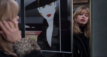 Movie still from “The First Wives Club” (1996), directed by Hugh Wilson – A woman standing in front of a picture of a woman with red lipstick; Close Up shot, Over the shoulder angle