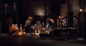 Movie still from “The First Wives Club” (1996), directed by Hugh Wilson – A group of people sitting in a room with candles; Wide shot, High angle