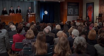 Movie still from “The First Wives Club” (1996), directed by Hugh Wilson – A man is giving a speech in front of an audience; Wide shot, High angle