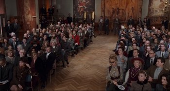 Movie still from “The First Wives Club” (1996), directed by Hugh Wilson – A crowd of people sitting in chairs in a room; Wide shot, High angle