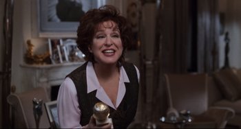 Movie still from “The First Wives Club” (1996), directed by Hugh Wilson – A woman smiling while holding a bottle of beer; Medium shot, Over the shoulder angle