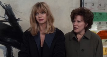 Movie still from “The First Wives Club” (1996), directed by Hugh Wilson – Two women sitting next to each other in front of a wall; Medium shot, Over the shoulder angle