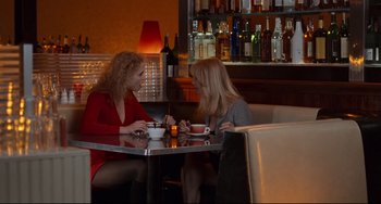 Movie still from “The First Wives Club” (1996), directed by Hugh Wilson – Two women sitting at a table in front of a wine bottle; Medium shot, Over the shoulder angle
