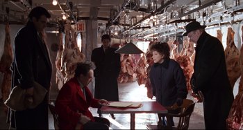 Movie still from “The First Wives Club” (1996), directed by Hugh Wilson – A group of people sitting at a table in a room full of meat; Wide shot, High angle