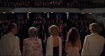 Movie still from “The First Wives Club” (1996), directed by Hugh Wilson – A group of women standing in front of a crowd of onlookers; Wide shot, High angle
