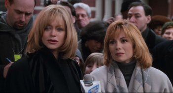 Movie still from “The First Wives Club” (1996), directed by Hugh Wilson – Two women are standing in front of a crowd of onlookers; Close Up shot, Over the shoulder angle