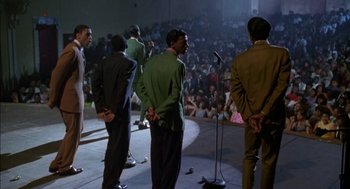 Movie still from “The Five Heartbeats” (1991), directed by Robert Townsend – A group of men standing in front of an audience; Wide shot, High angle